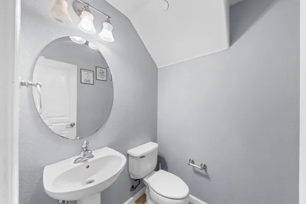 a view of a hallway with wooden floor and a bathroom