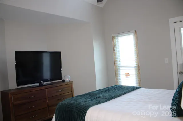 a bedroom with a flat screen tv and a window