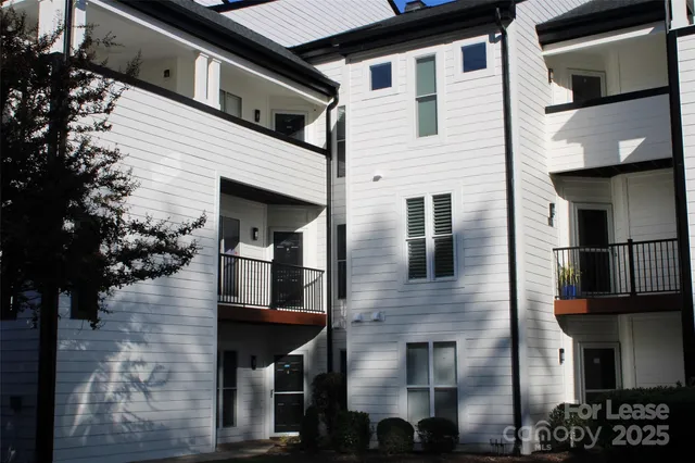 a front view of a house with glass windows and a tree