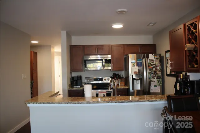 a kitchen with stainless steel appliances kitchen island granite countertop a refrigerator and stove