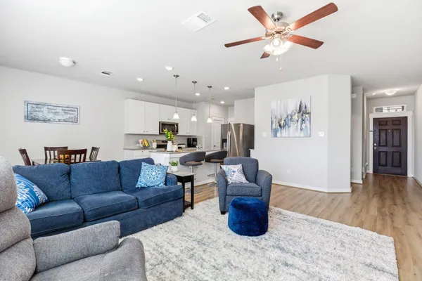 a living room with furniture kitchen view and a chandelier