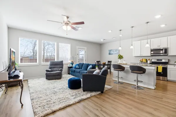 a living room with furniture kitchen view and a large window