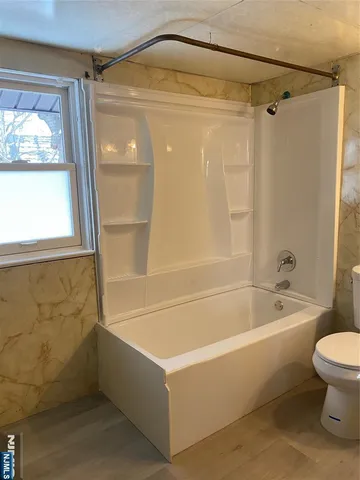 a bathroom with a tub a toilet and a shower
