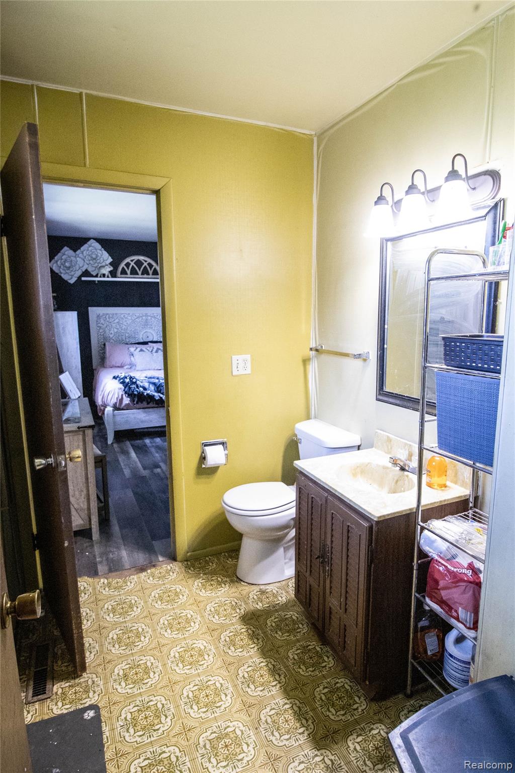 10340 Farrand Road Montrose, MI 48457 - Photo 28 of 33 Bathroom with patterned floor tiles, a single vanity with a built-in sink, a wall-mounted mirror, and a three-light fixture