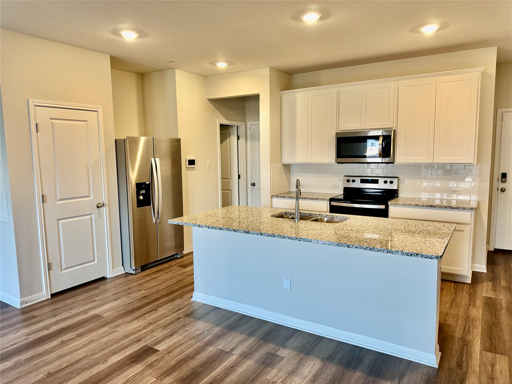 165 Calcite Road, Unit 3 Kyle, TX 78640 - Photo 2 of 17 a large kitchen with stainless steel appliances granite countertop a refrigerator a stove top oven a sink and dishwasher with wooden floor
