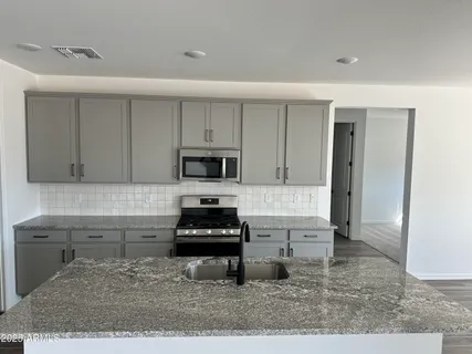 a kitchen with stainless steel appliances kitchen island granite countertop a stove a sink and a white cabinets