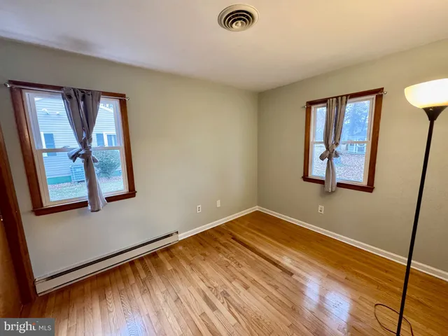 a view of an empty room with window and wooden floor