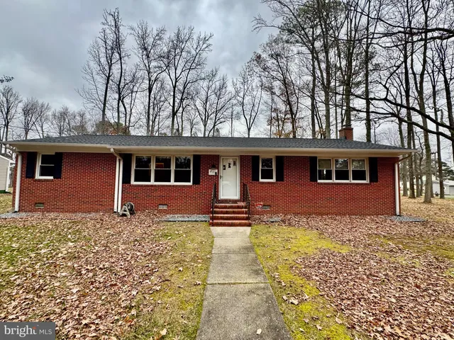 a living room with couches bookshelf and a large window with wooden floor