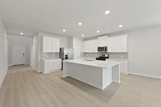 a kitchen with stainless steel appliances white cabinets and wooden floor