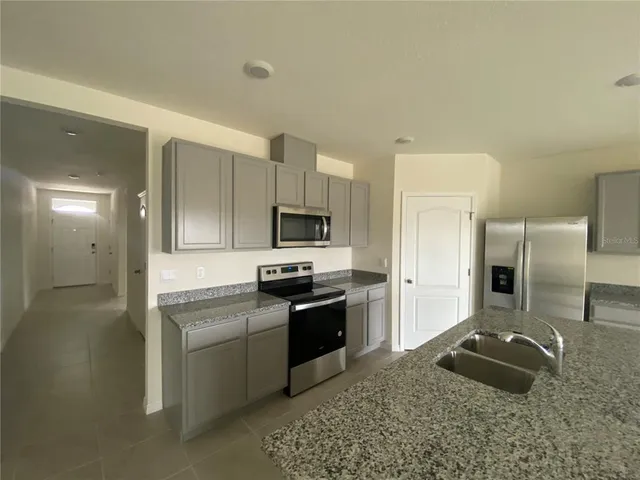 a kitchen with granite countertop a sink cabinets and stainless steel appliances