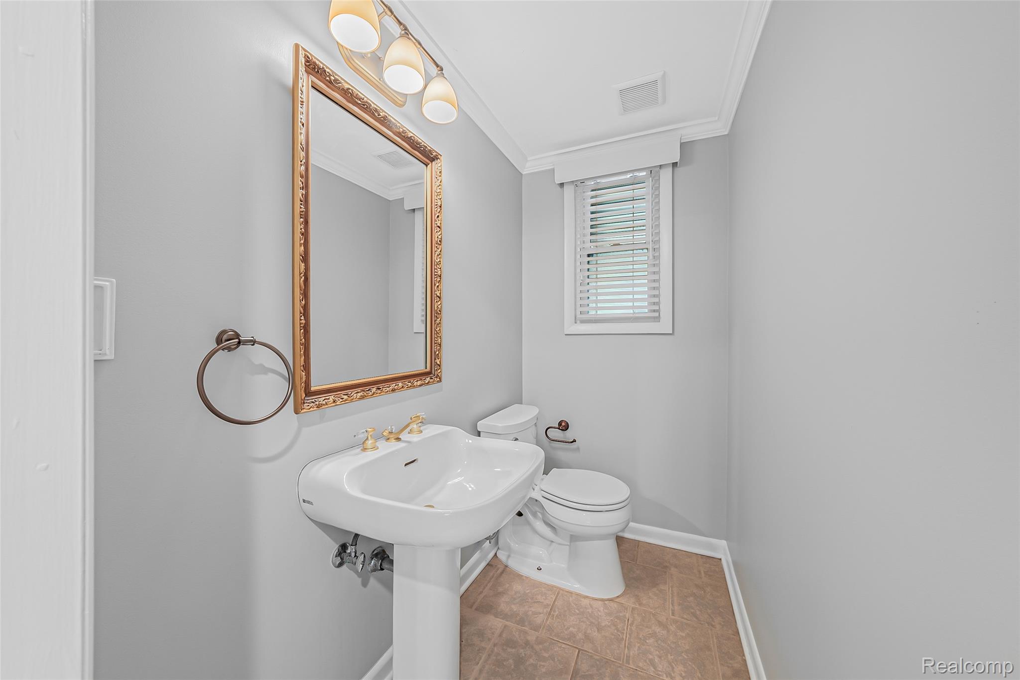 2329 Rutherford Road Bloomfield Hills, MI 48302 - Photo 26 of 46 Pedestal sink with brass-finish faucet, framed mirror with integrated lighting, and a window with horizontal blinds