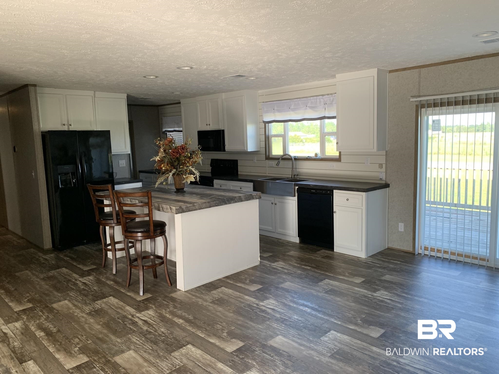 16876 County Road 87 Elberta, AL 36530 - Photo 6 of 13 Kitchen featuring white cabinetry, a breakfast bar area, black appliances, a center island, and sink