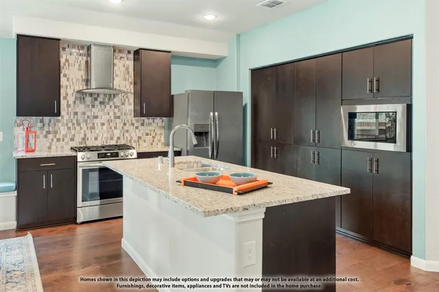 a kitchen with stainless steel appliances kitchen island granite countertop a refrigerator a stove and a sink