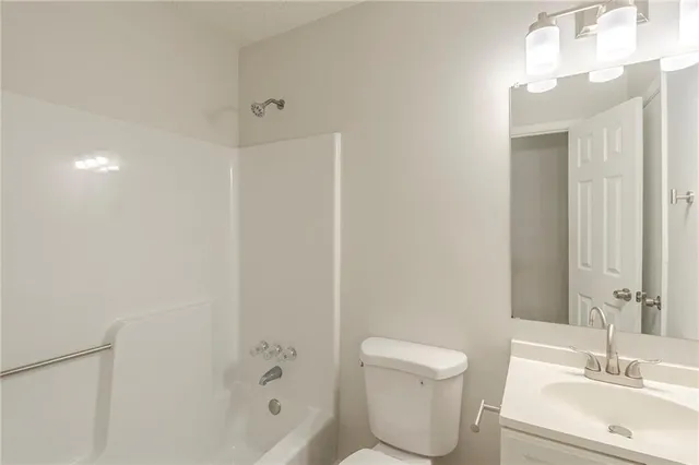 a bathroom with a toilet a sink a mirror a shower and vanity