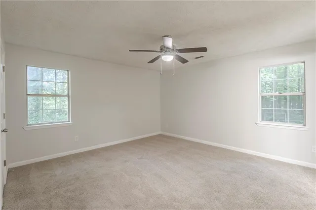 an empty room with a window and ceiling fan