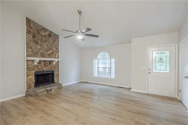 an empty room with windows fireplace and wooden floor