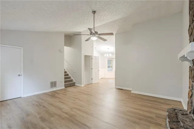 an empty room with wooden floor and ceiling fan