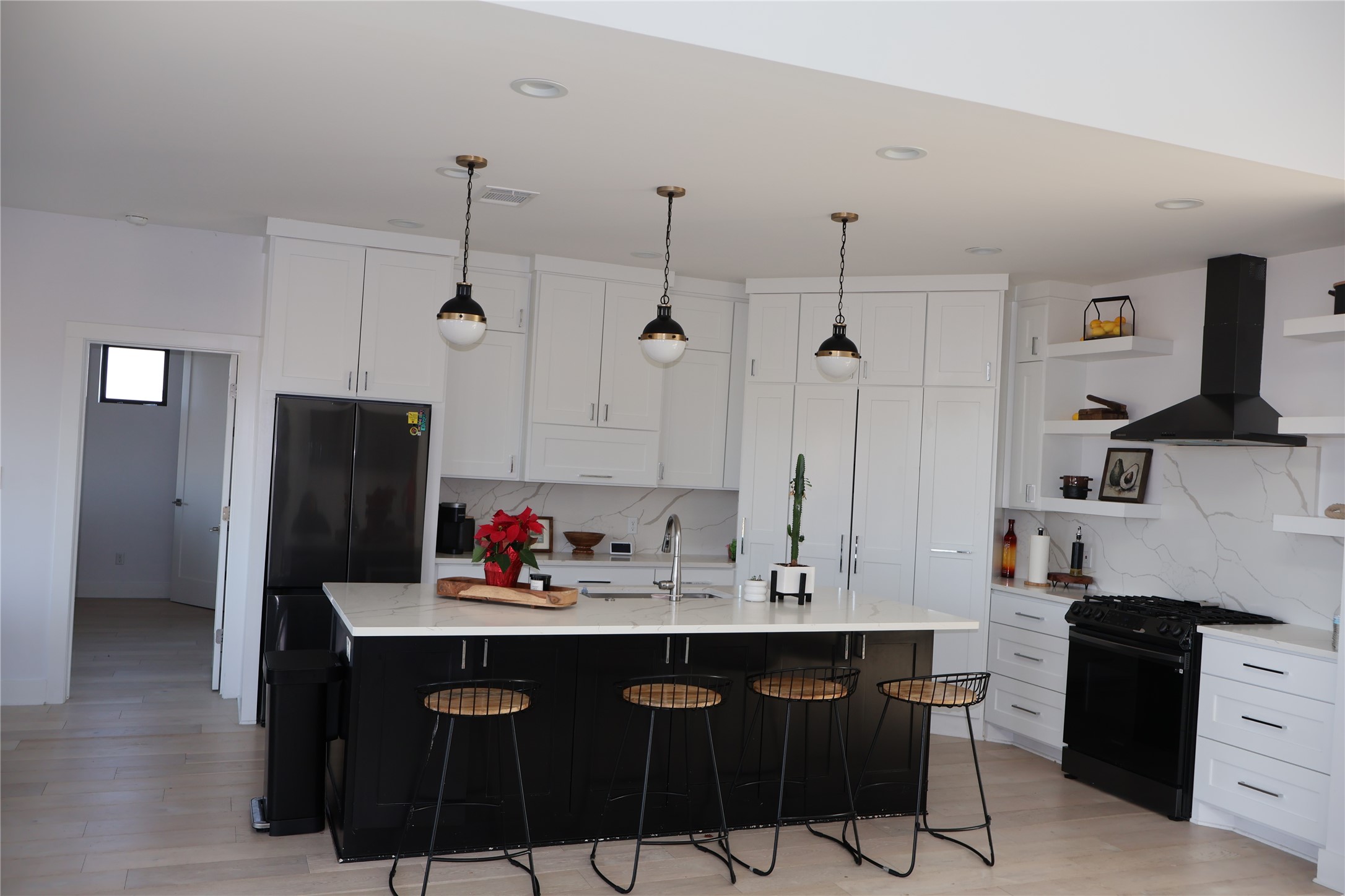 17216 Lund - Carlson Road Elgin, TX 78621 - Photo 5 of 17 Kitchen featuring black appliances, dark cabinetry, wall chimney exhaust hood, and pendant lighting