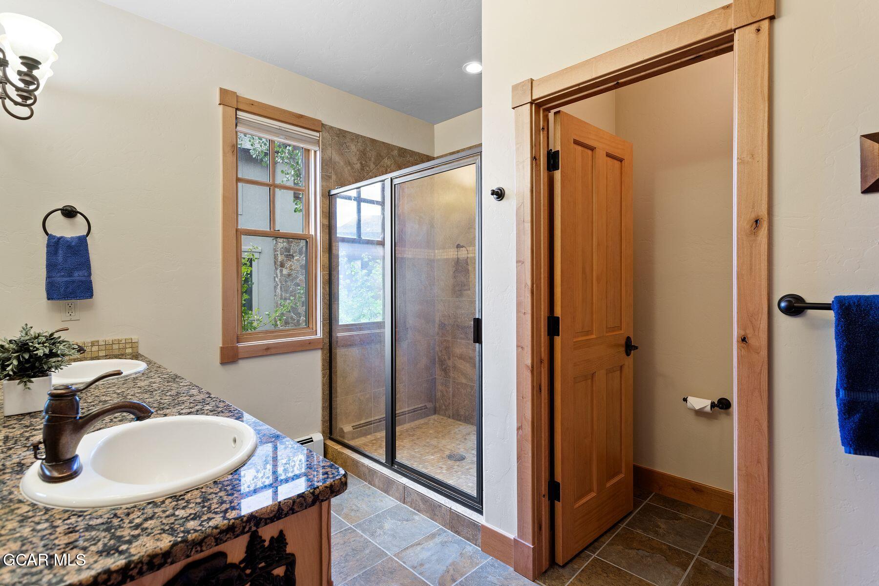 445 Trappers Way Fraser, CO 80442 - Photo 20 of 37 a bathroom with a granite countertop sink mirror vanity and shower