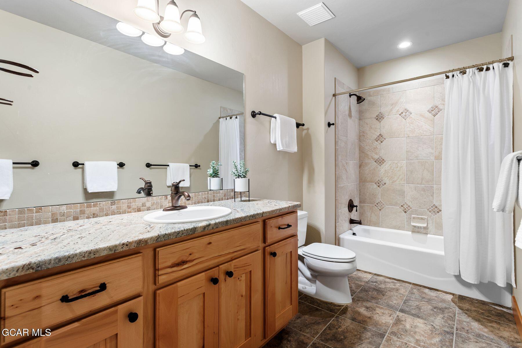 445 Trappers Way Fraser, CO 80442 - Photo 31 of 37 a bathroom with a granite countertop sink a toilet a mirror a bathtub and shower
