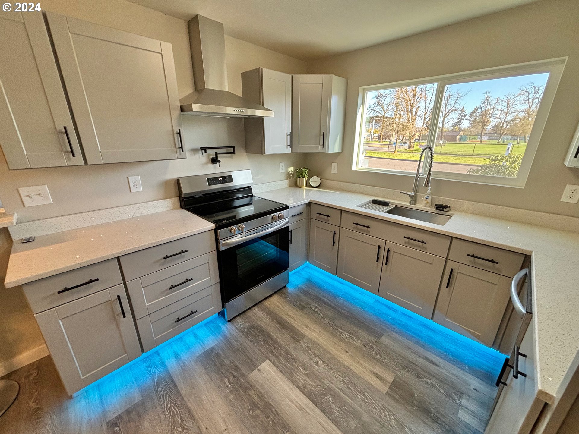 2140 J Street Springfield, OR 97477 - Photo 11 of 23 a kitchen with stainless steel appliances a stove a sink dishwasher and white cabinets with wooden floor