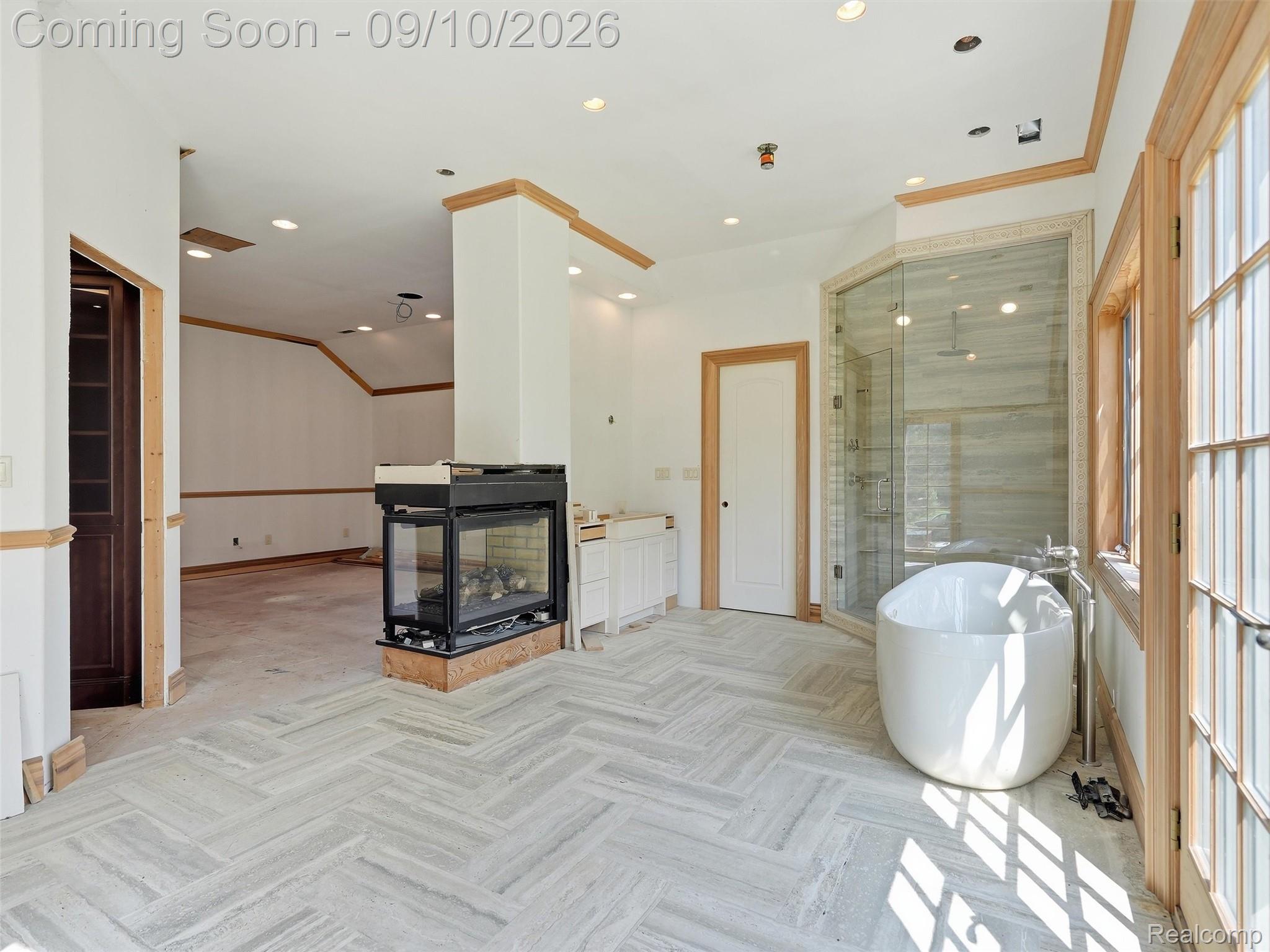 61400 Romeo Plank Road Ray, MI 48096 - Photo 61 of 99 Herringbone-patterned tile flooring, a freestanding soaking tub, a glass-enclosed shower, a built-in fireplace, and wood trim accents