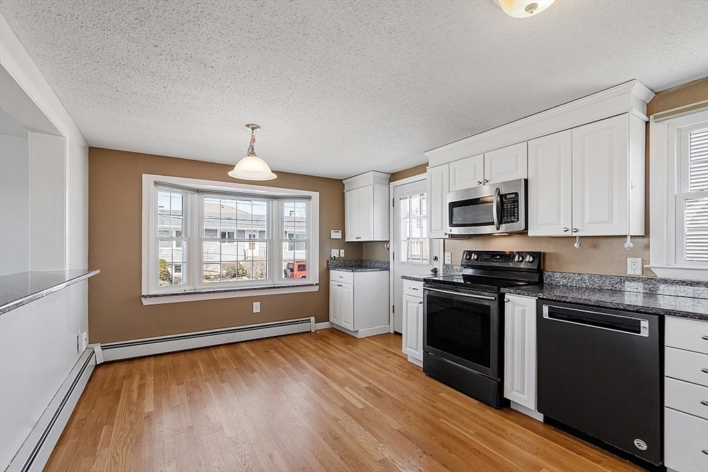 163 Mills Avenue Revere, MA 02151 - Photo 18 of 22 a kitchen with granite countertop a stove top oven a sink dishwasher and a microwave oven with cabinets