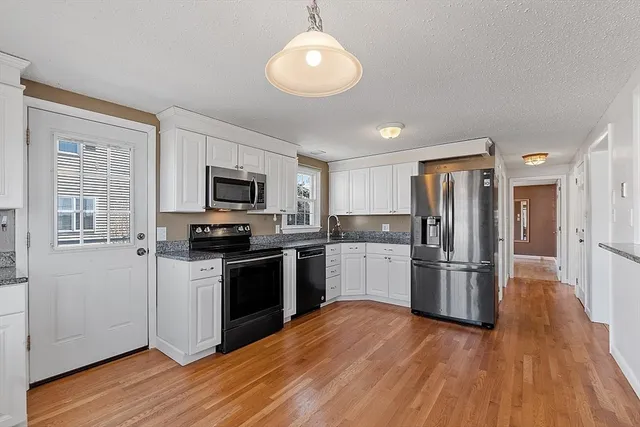 a kitchen with granite countertop a refrigerator stove and microwave