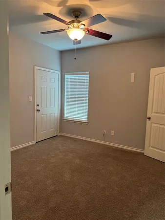 an empty room with windows and fan