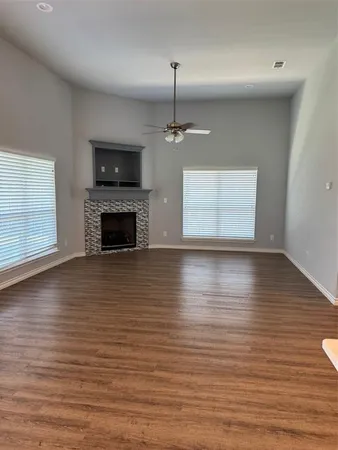 an empty room with wooden floor fireplace and windows