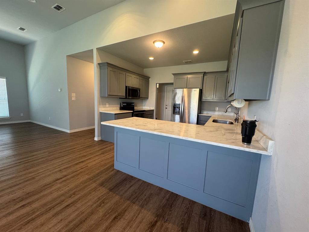 792 East Northside Drive Pilot Point, TX 76258 - Photo 7 of 18 a kitchen with stainless steel appliances wooden cabinets and a stove top oven