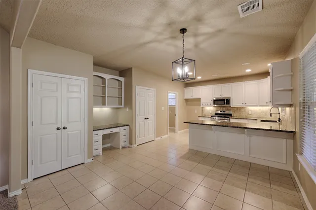 a kitchen with granite countertop stainless steel appliances a sink a refrigerator a stove a microwave and cabinets