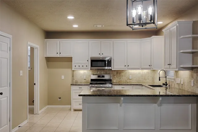a kitchen with granite countertop stainless steel appliances and white cabinets