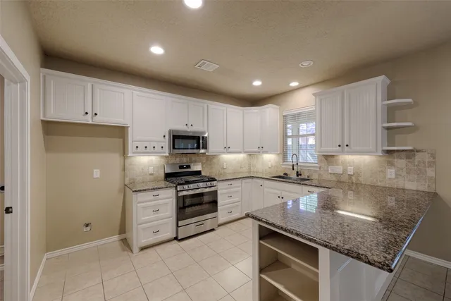 a kitchen with granite countertop white cabinets and appliances