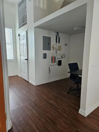 an empty room with wooden floor staircase and windows