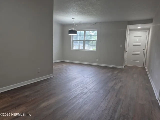 an empty room with wooden floor chandelier and windows