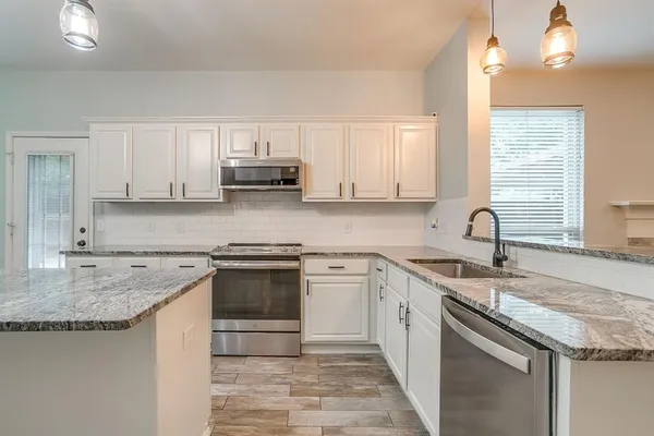 a kitchen with stainless steel appliances granite countertop a sink stove and cabinets