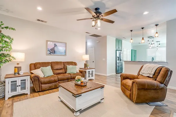 a living room with furniture kitchen view and a chandelier