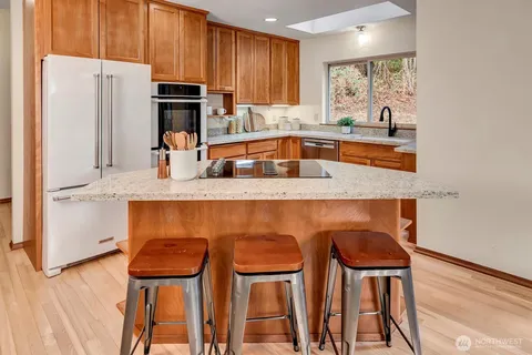 a kitchen with stainless steel appliances granite countertop a refrigerator a stove a sink and white cabinets with wooden floor