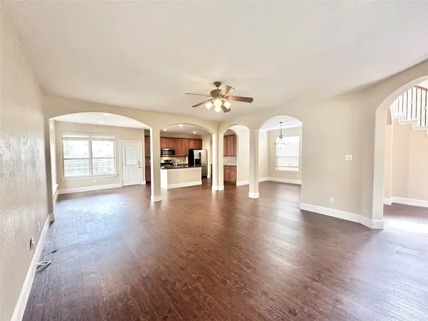 an empty room with wooden floor chandelier and windows