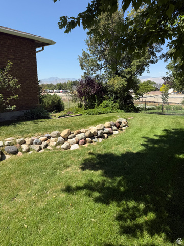 328 Heather Ridge Circle Sandy, UT 84070 - Photo 30 of 32 Expansive green lawn with a decorative rock border