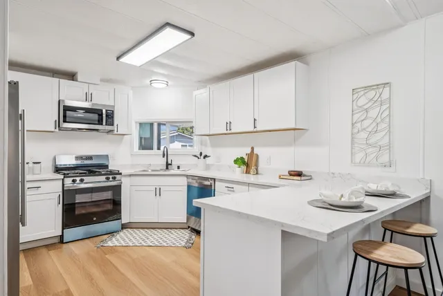 a kitchen with stainless steel appliances white cabinets a stove and a microwave