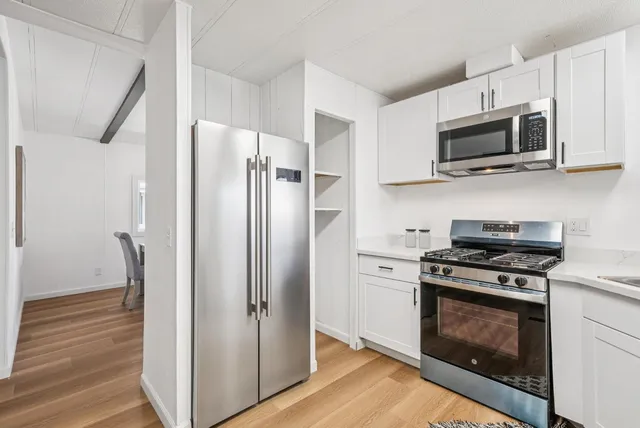a living room with furniture wooden floor and a kitchen view