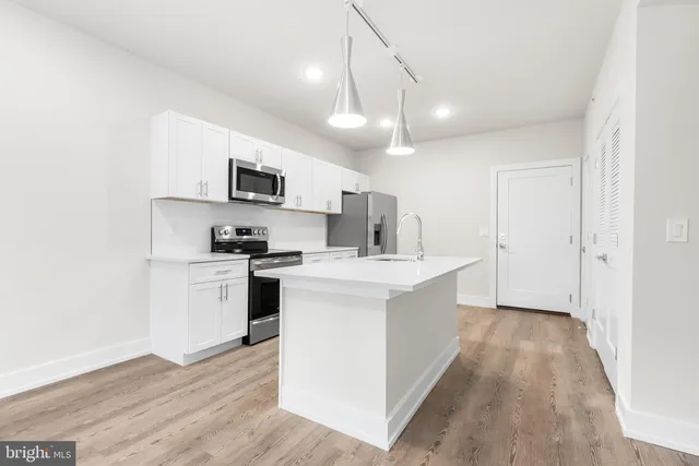 a kitchen with kitchen island a sink stainless steel appliances and cabinets