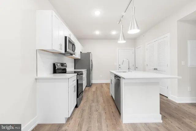 a kitchen with stainless steel appliances granite countertop a sink a stove a refrigerator and island with wooden floor