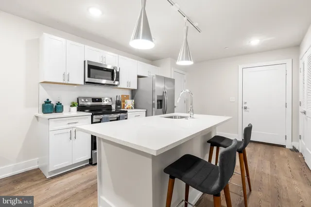 a kitchen with stainless steel appliances kitchen island a wooden floor and white cabinets