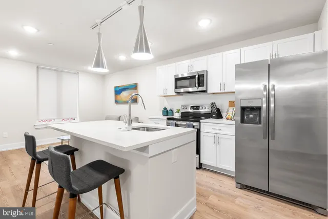 a kitchen with a sink stainless steel appliances and white cabinets