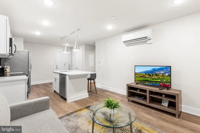 a living room with furniture a flat screen tv and kitchen view