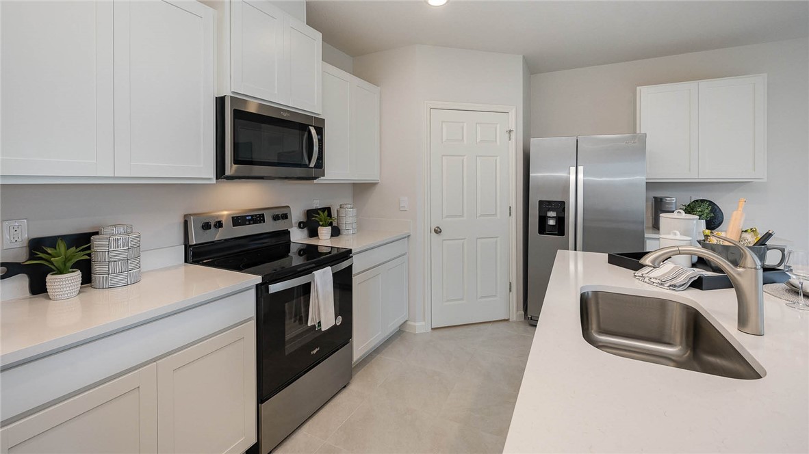 608 Lawson Street Sebastian, FL 32958 - Photo 12 of 30 a kitchen with stainless steel appliances granite countertop a sink a microwave a refrigerator a stove and white cabinets