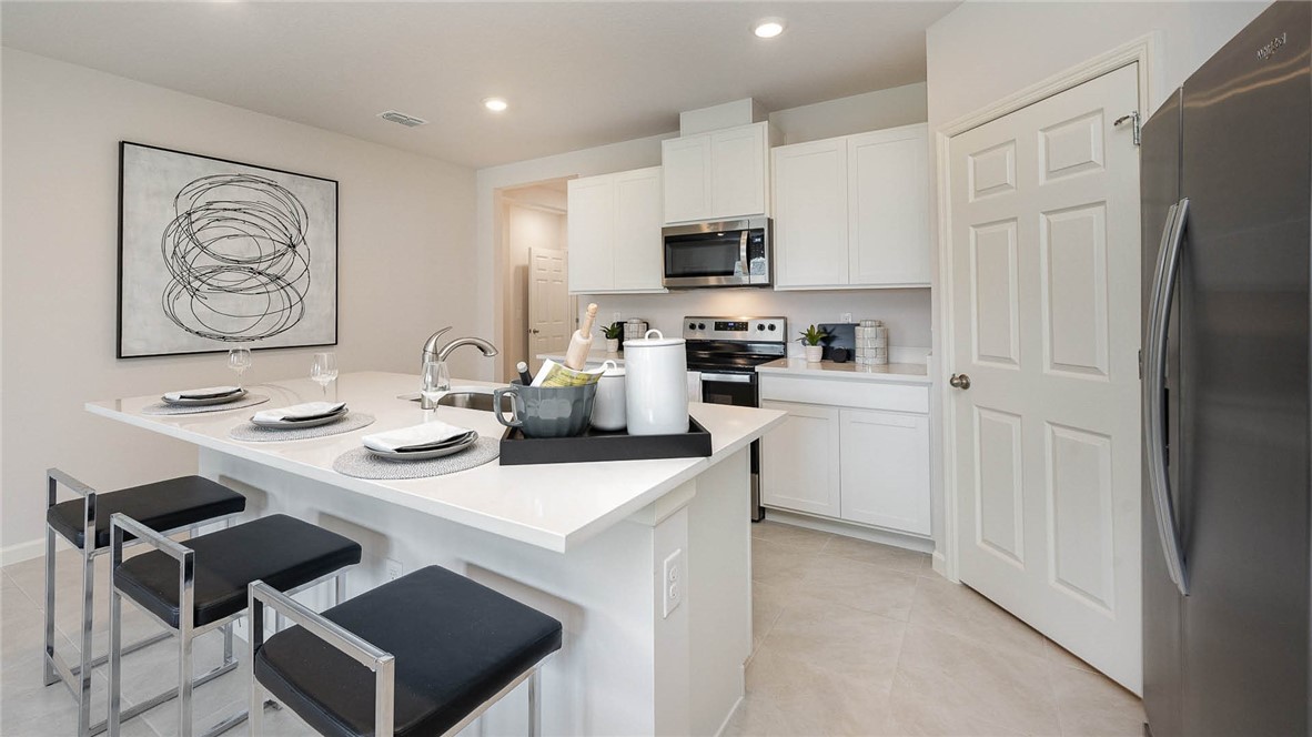 608 Lawson Street Sebastian, FL 32958 - Photo 9 of 30 a kitchen with stainless steel appliances a stove a sink a refrigerator and white cabinets with wooden floor